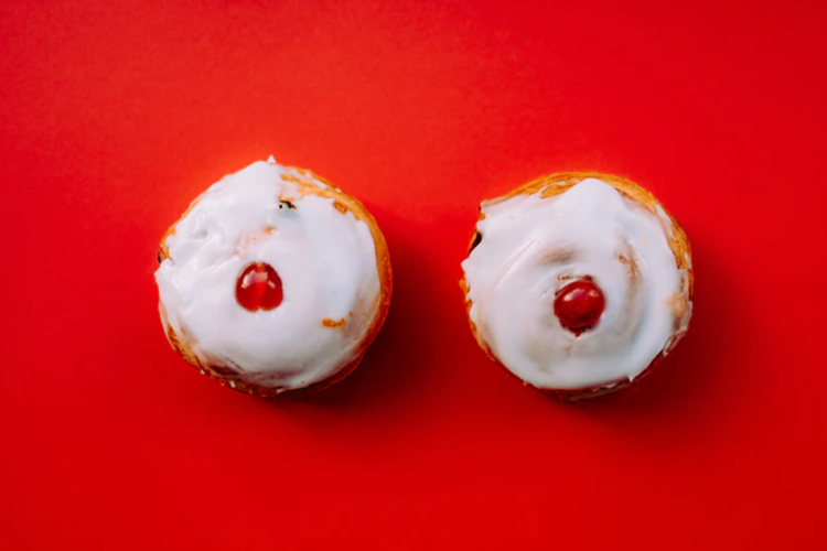 Close up of cinnamon buns with cherries, a fun depiction of the naked breasts